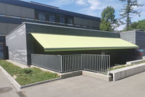 grüne Sonnenstore Schulhaus Lyss, 11m breite Sonnenstore, farbige Sonnenstore